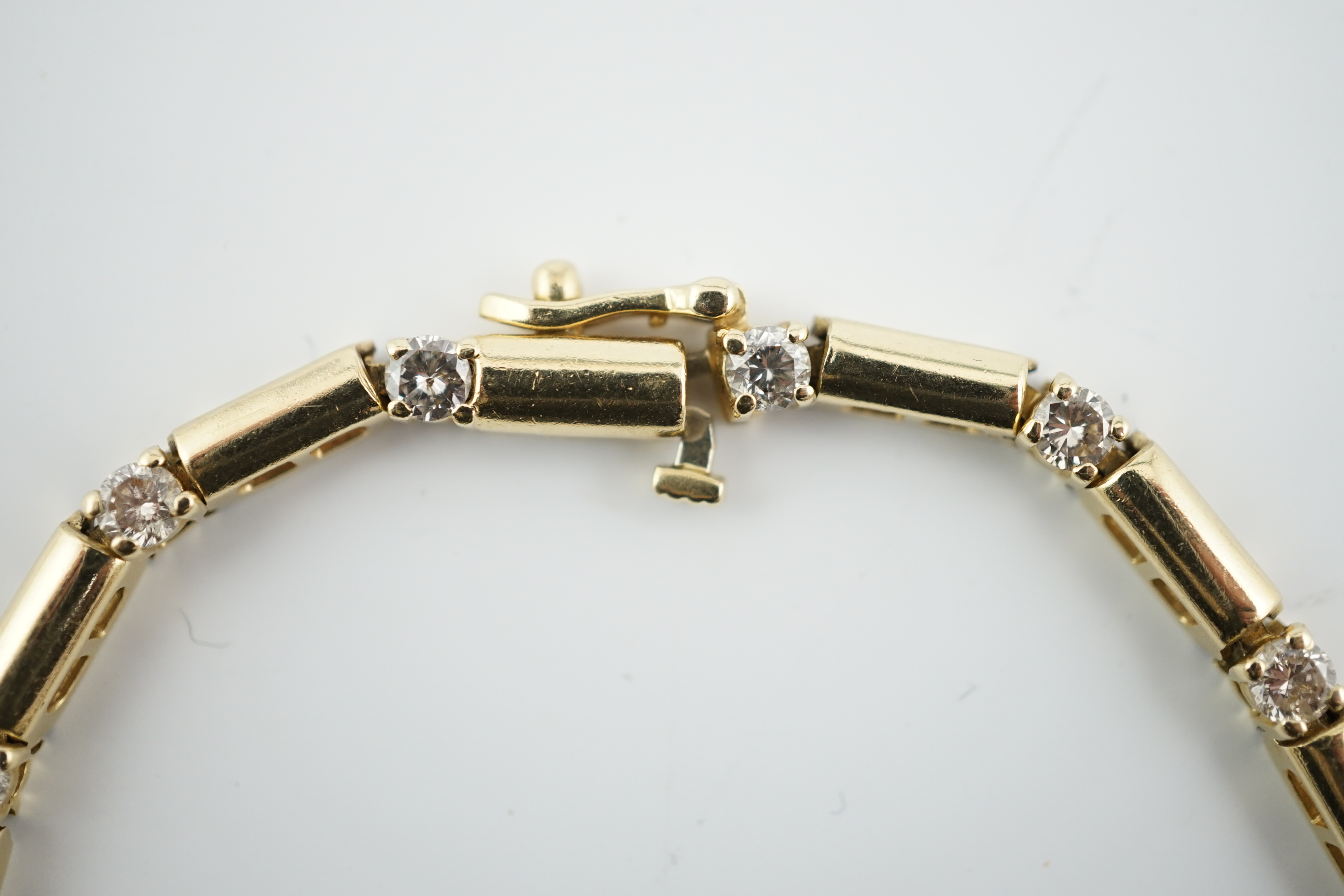 A modern 14k gold and fifteen stone diamond set line bracelet